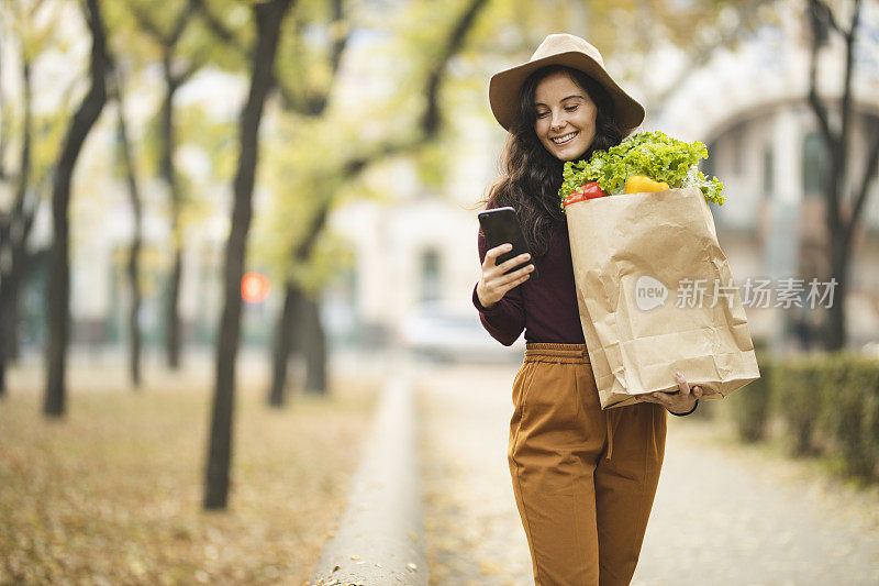 拿着购物袋的女人用手机给别人发短信