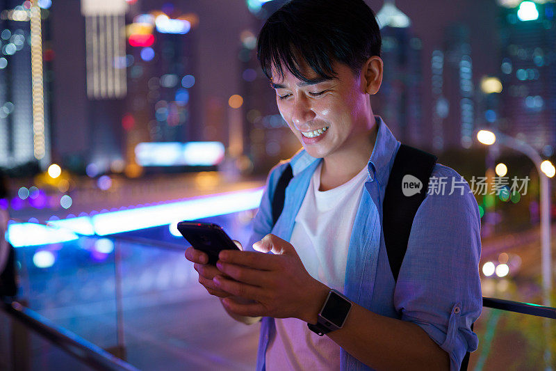 年轻的亚洲男子在晚上使用智能手机