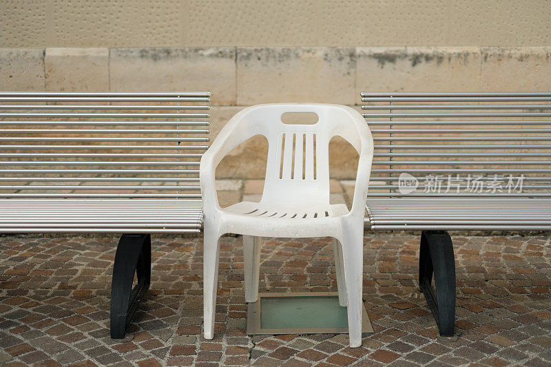两个公共长椅之间的塑料椅子