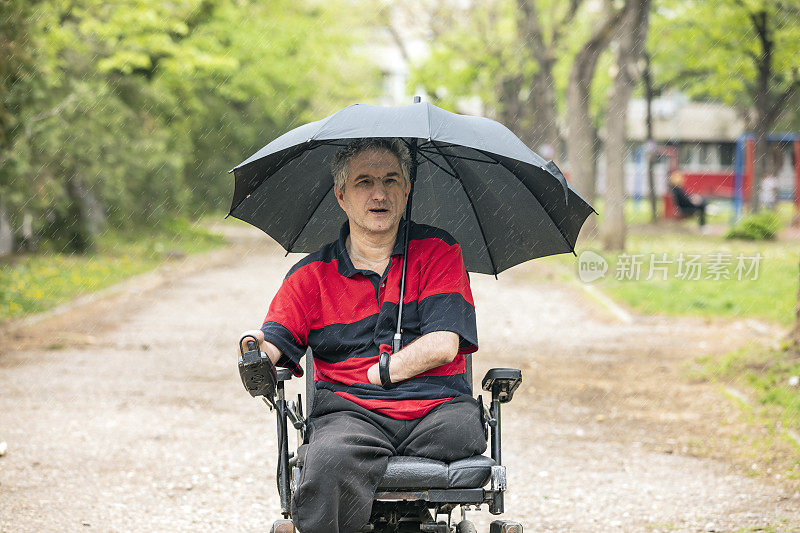 在雨天坐电动轮椅的残疾人在移动