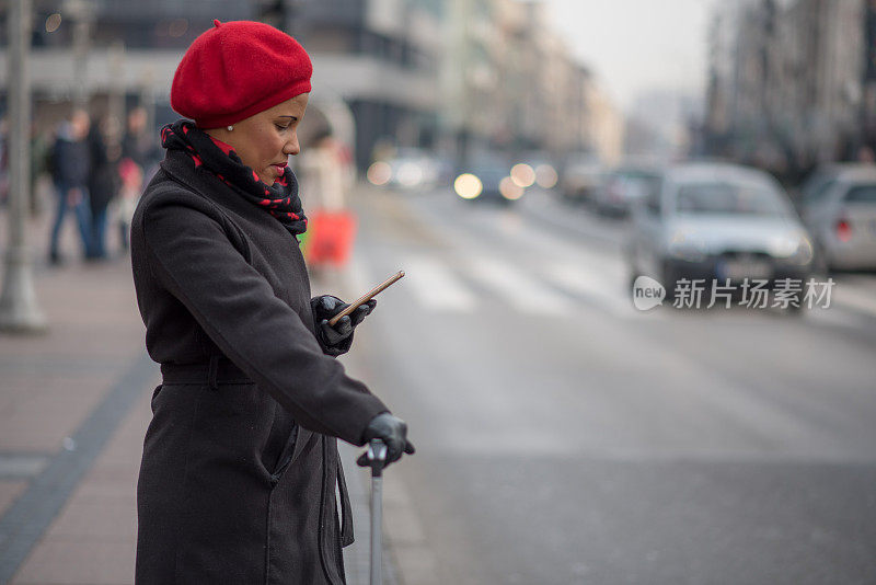 漂亮的肤色女人使用手机应用程序得到一个出租车