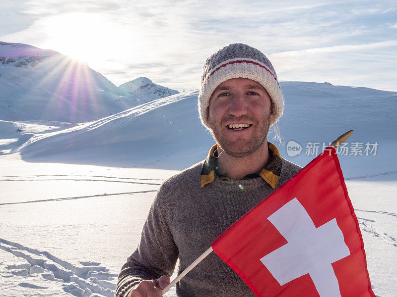 在瑞士阿尔卑斯山雪山上的男人的肖像拿着瑞士国旗