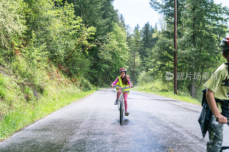 一个十几岁的小女孩在森林地区的乡间小路上骑着自行车