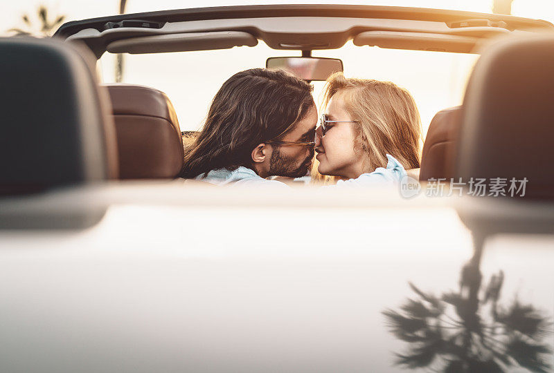 幸福的情侣在敞篷车里接吻-浪漫的人们在热带城市的公路旅行中有温柔的时刻-爱情关系和青年度假的生活方式概念