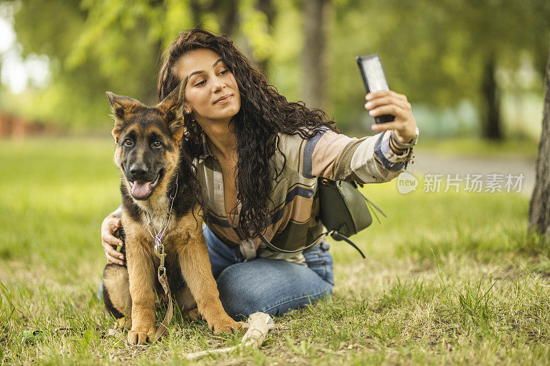 一个女人和她的狗在用手机自拍