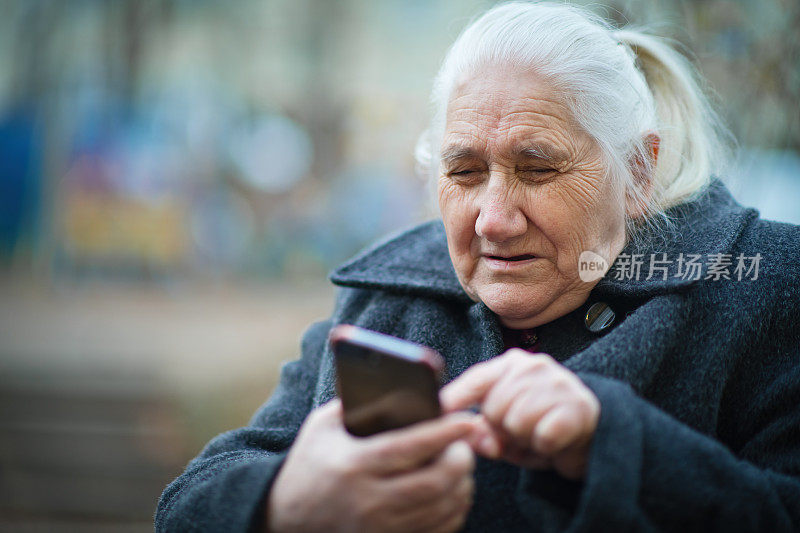 高级女性在户外使用智能手机并戴上防护口罩