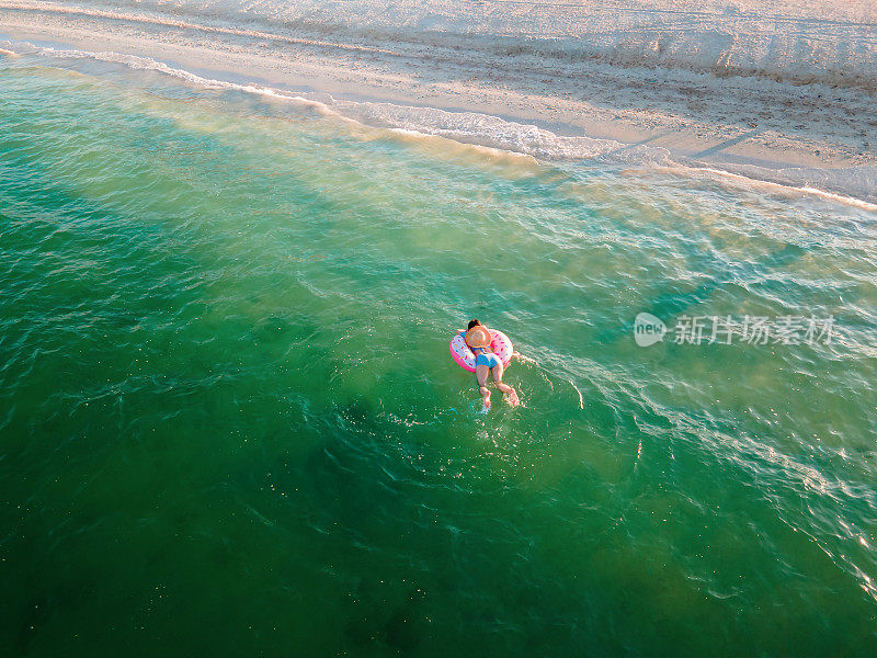 女人游泳和漂浮在海边的水与甜甜圈浮动鸟瞰图