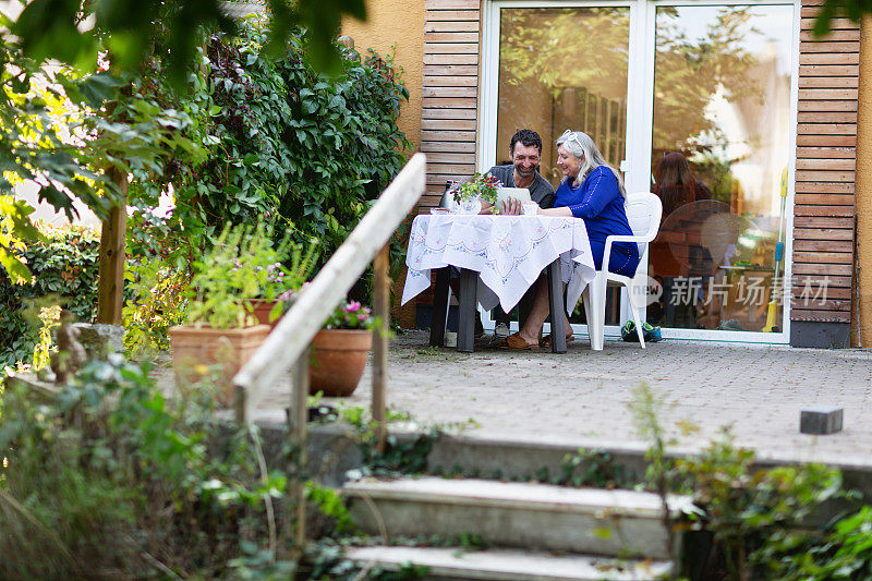 夫妇在后院的桌子上使用电子平板电脑