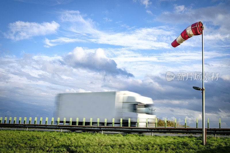 在一个刮风的日子里，一辆卡车驶过高速公路附近的风标