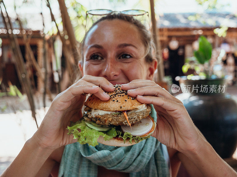 在咖啡厅吃素食汉堡的女人