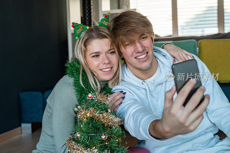 年轻夫妇拿着手机在家里过圣诞节