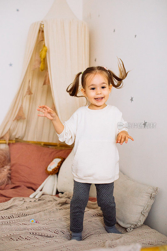 快乐的小女孩蹦蹦跳跳玩床
