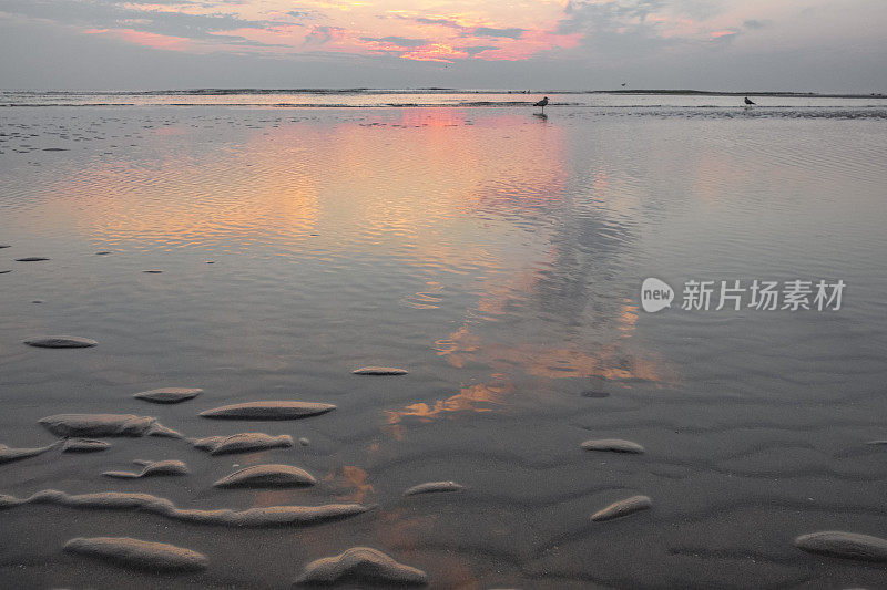 在平静的海面上，夏日日落时沙滩上的涟漪