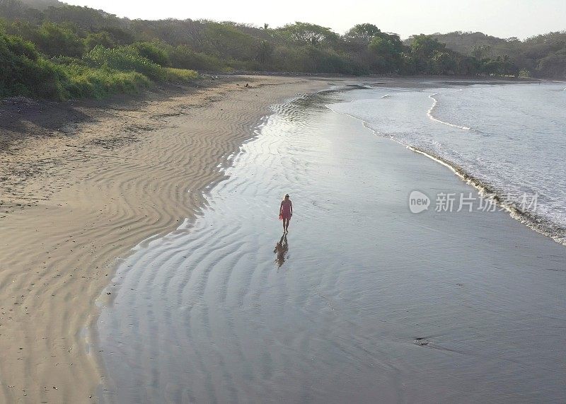 鸟瞰图的女人走下沙滩在日出