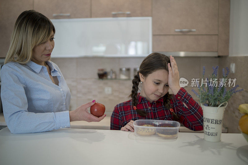 妈妈送女儿去学校，给她一个苹果。