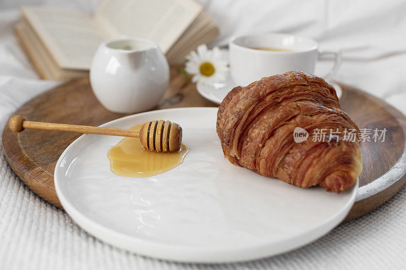 把蜂蜜牛角面包放在早餐茶盘上