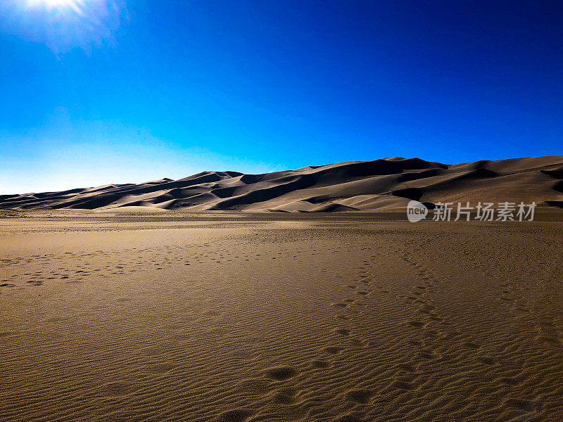 太阳越过脚印在大沙丘科罗拉多