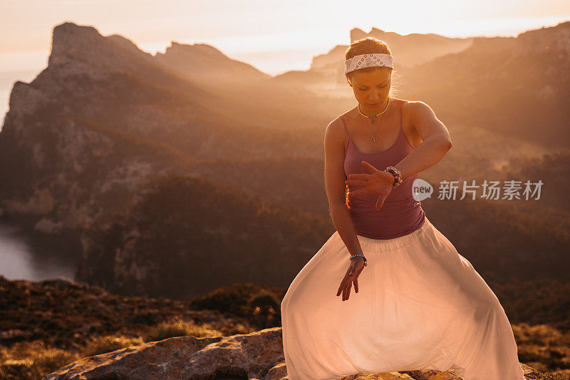 美丽的年轻女子在一个山区的日出打太极