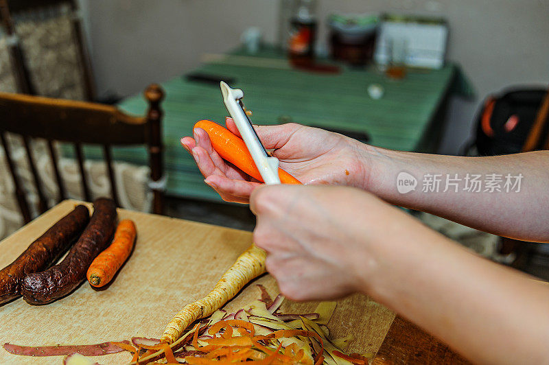 一位女厨师正在厨房里剥生胡萝卜。