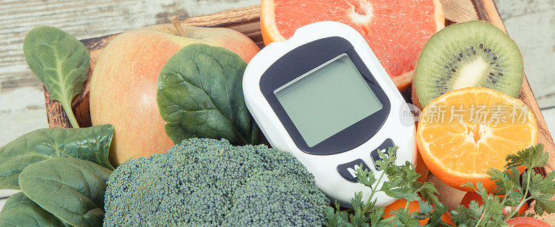 血糖测量仪用于测量和检查血糖水平和水果和蔬菜。糖尿病、健康生活方式和营养的概念