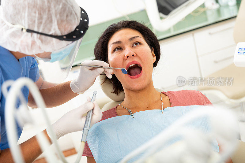 女病人坐在牙科椅上。牙医正在近距离治疗女病人