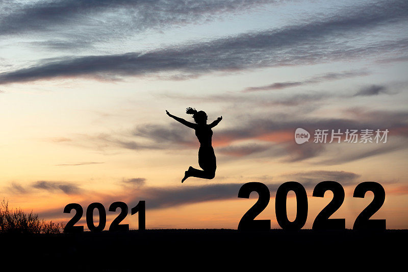 一个女人的剪影在2022年的日落在山上跳