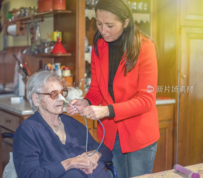 家庭关爱家庭。女儿帮助年老的母亲用胃管治疗吞咽困难