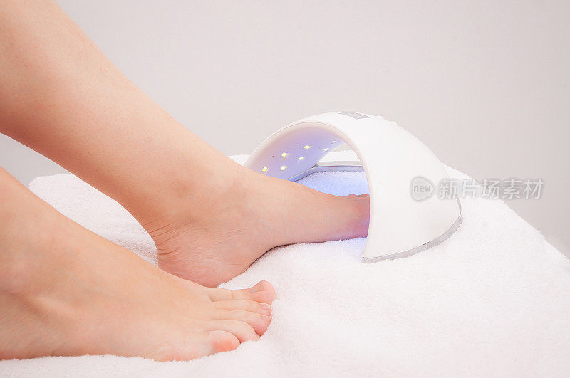 一名女子在水疗沙龙用紫外线晒脚趾甲。