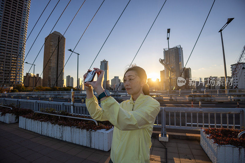 女运动员在慢跑时拍摄日落照片