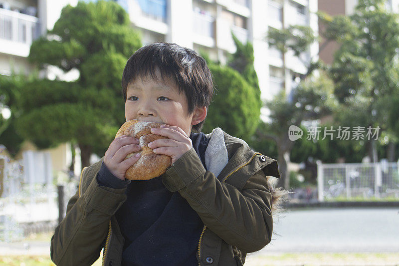 男孩在户外吃着一个大面包