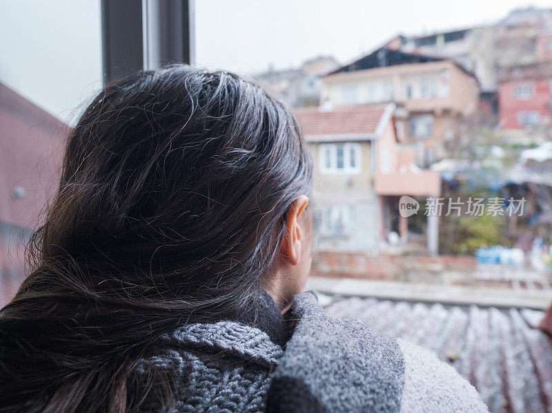 孤独悲伤的年轻女子看着贫民窟的风景后降雪