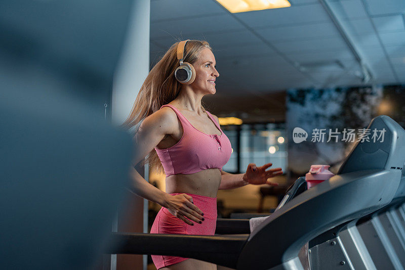 一个女人在健身房的跑步机上慢跑