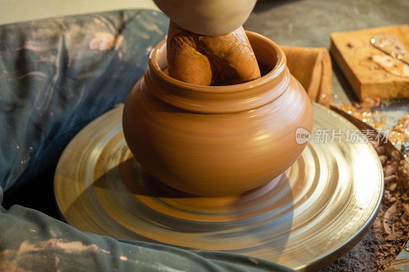 陶工师傅的手塑造外面的黏土。陶艺车间陶轮上的陶罐