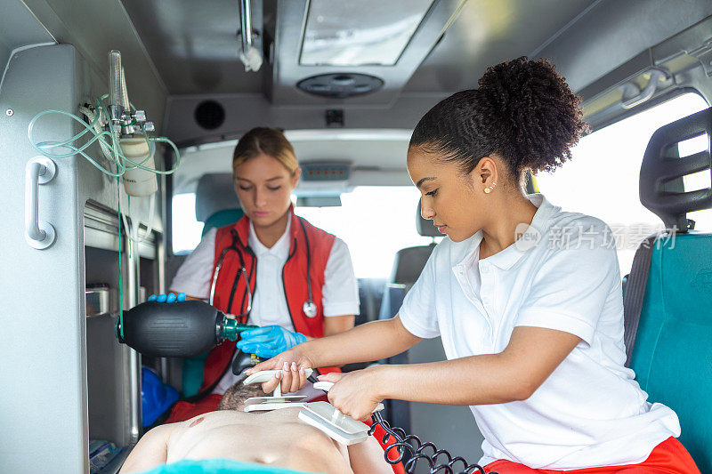 辅助人员使用除颤器(AED)进行基本心肺复苏。急救护理助理在救护车上放置硅胶人工复苏器。