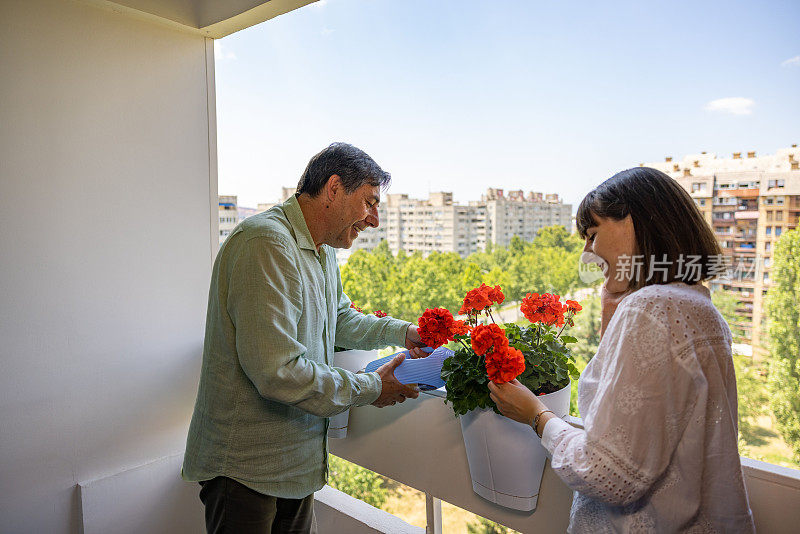 十几岁的白人女儿和她的父亲在阳台上照顾室内植物