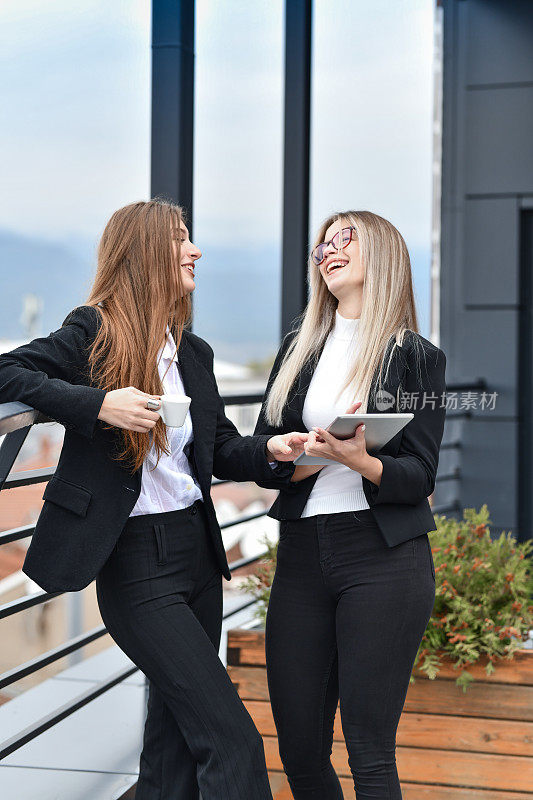 两名笑着的女企业家在咖啡休息时间用平板电脑上的视频放松
