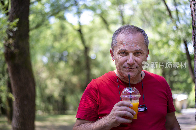 精力充沛的老人在公园锻炼，休息和喝橙汁，过着健康的生活。