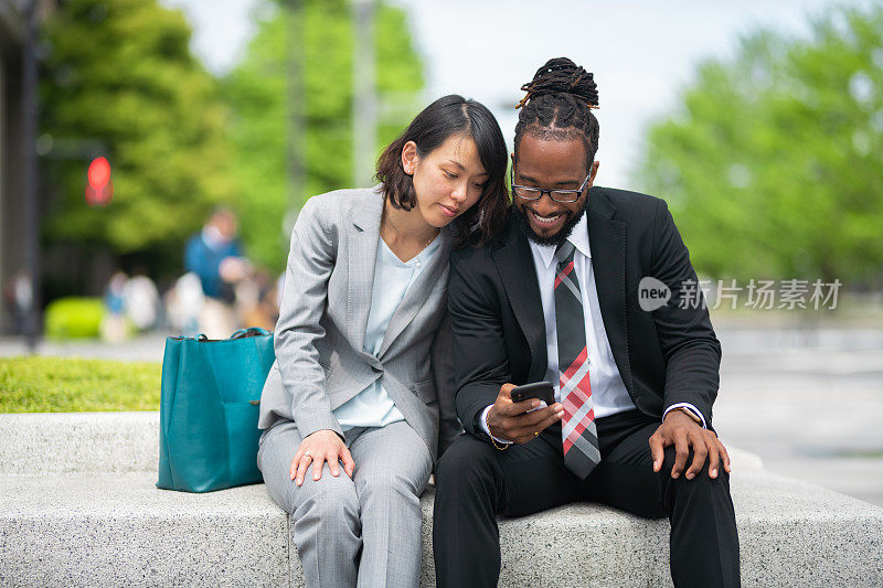 多民族的经商夫妇坐在公园的混凝土长凳上