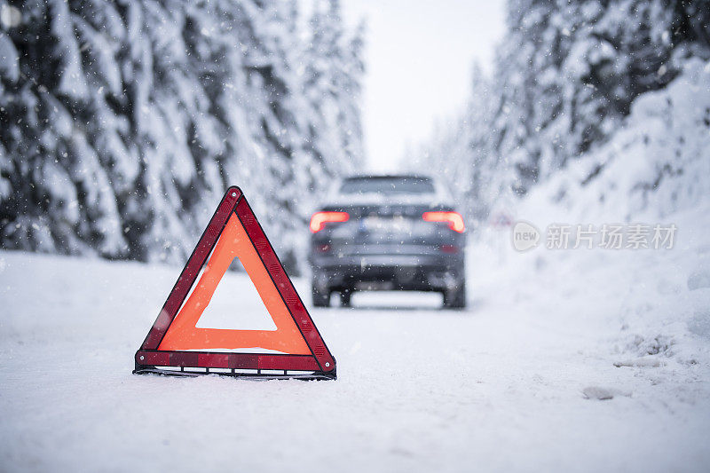 一辆吉普车被困在雪路上，有危险标志保护。