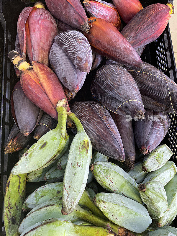 农产品市场货架显示一堆新鲜的香蕉花和大蕉(Musa)在塑料板条箱，绿色烹饪香蕉和香蕉心，从水果和蔬菜食品部出售的超市，高架视图