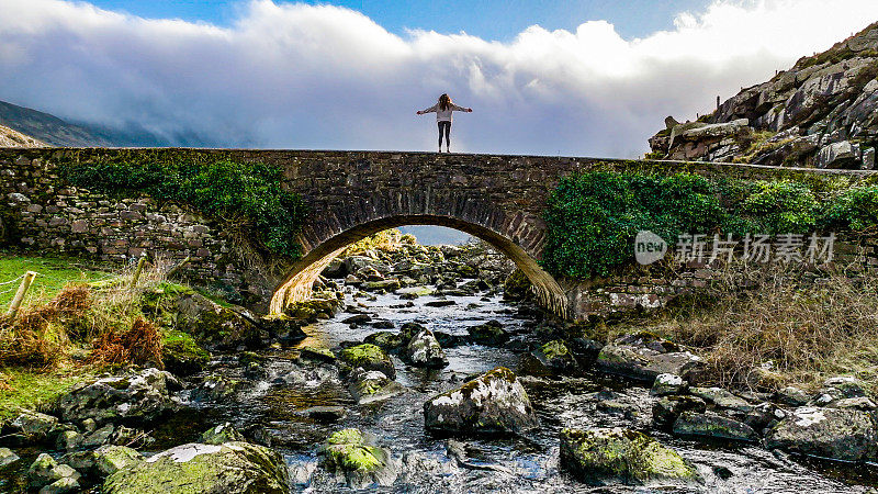 爱尔兰克里郡邓洛峡谷鸟瞰图，女人在古老的石桥上看自然，在自然中自由，在自然中坚强的女人，向自然致敬的女人，电影般的自然照片，放松冥想的自然