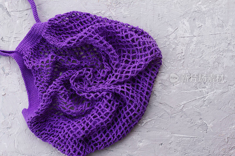 针织紫色网串袋，灰色混凝土背景与石膏珠