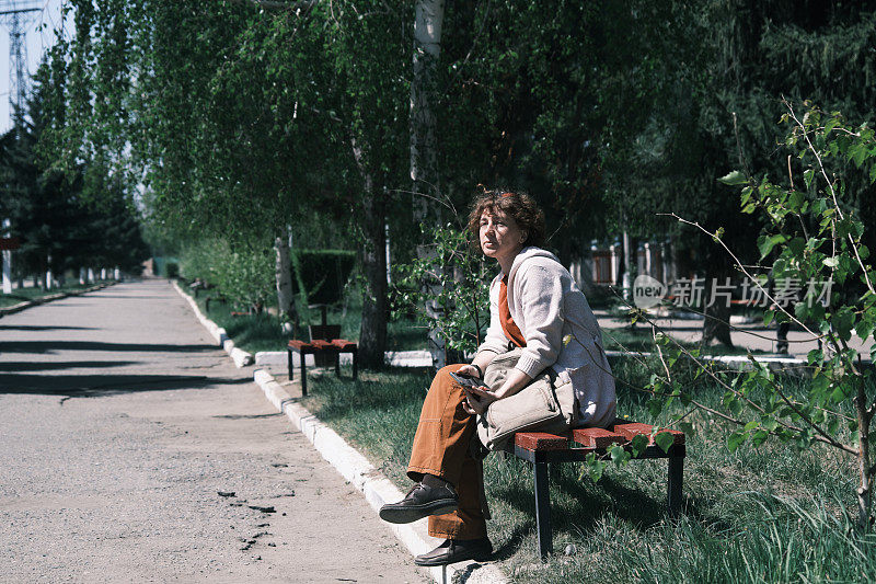 春天的城市公园里，一个女人坐在长椅上打电话