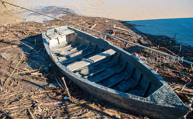 那艘旧船被汹涌的河水冲走的残骸包围着