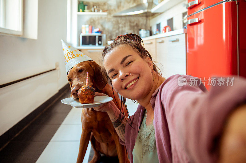 年轻女子和她的狗狗一起庆祝生日，并在自拍