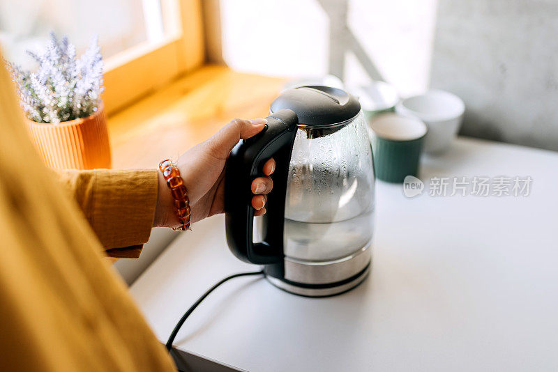 一个无法辨认的女人在厨房用水壶的特写镜头