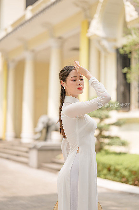 快乐的越南女孩穿着传统的白色敖代服装，戴着越南帽子