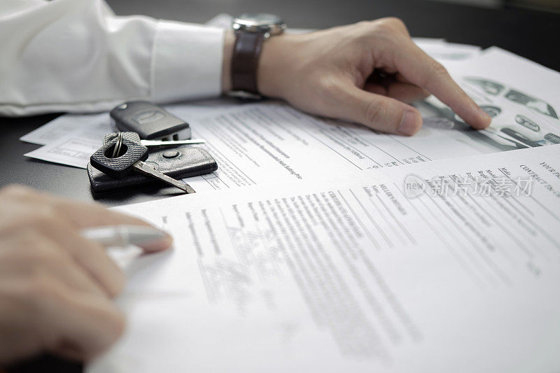 负责签署汽车保险文件或租赁文件。在合同或协议上书写签名。买卖新车或二手车。木桌上的车钥匙。保证或保证