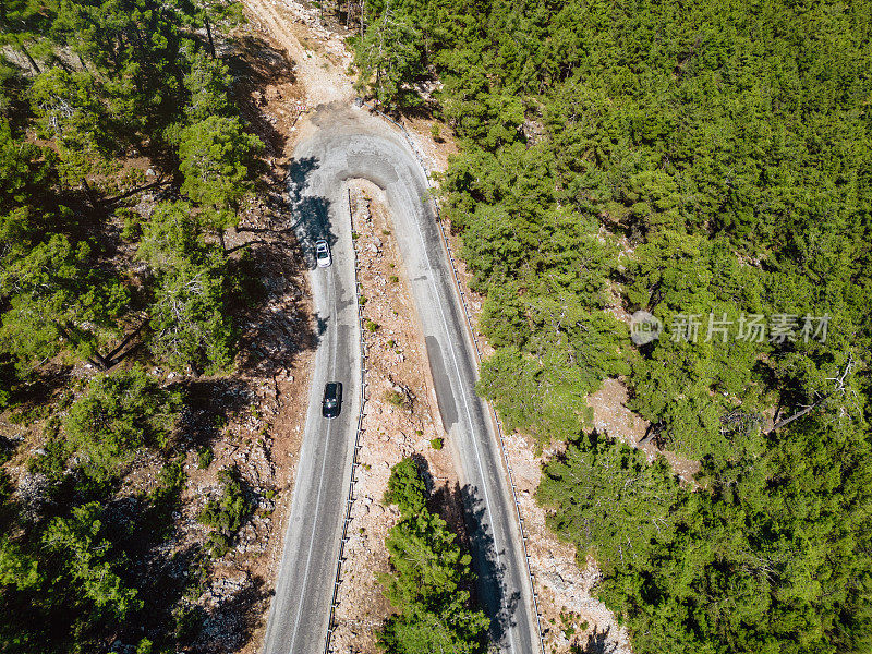 在森林山区的道路上行驶的车辆用无人机拍摄沥青弯道