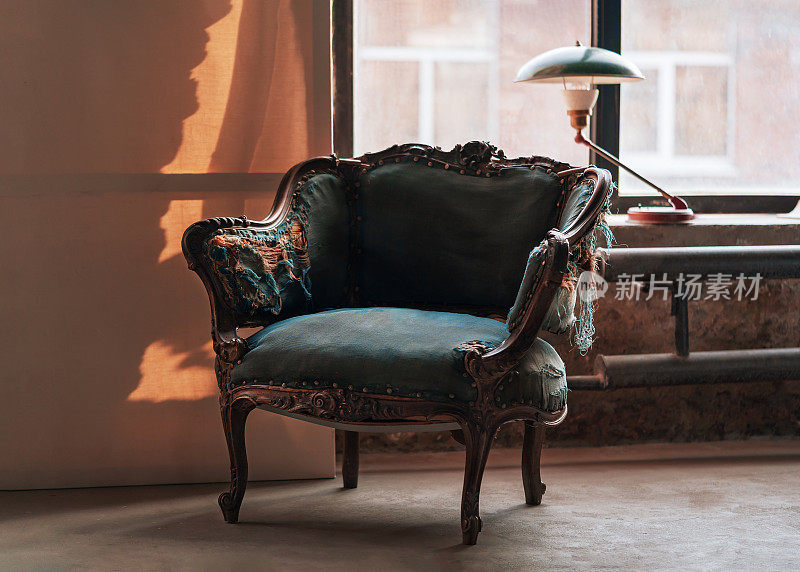 经典复古扶手椅与美丽的雕刻木制元素和蓝色撕裂室内装饰在垃圾房间与绿色的灯在窗台上。